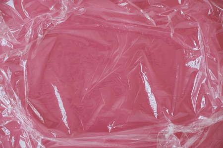 Wrinkled transparent plastic texture on an pink background. Transparent cellophane texture on an pink backing. Top view. Copy, empty space for text.の写真素材