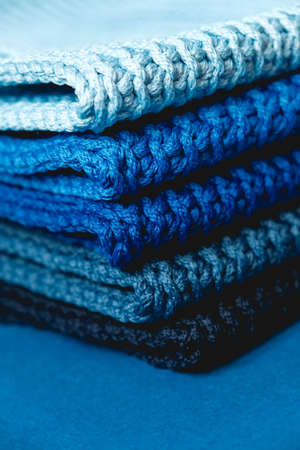 Stack of knitted material from threads of dark blue, light blue, gray colors on a blue background. Copy, empty space for text.の写真素材