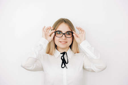 Portrait of a positive beautiful blonde woman wearing stylish white shirt holding her glasses on a white background. Copy, empty space for text.の写真素材