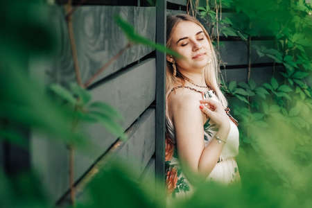 Portrait of a beautiful blonde girl with natural beauty in a green leaves trees. Copy, empty space for text.の写真素材