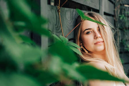 Portrait of a beautiful blonde girl with natural beauty in a green leaves trees. Copy, empty space for text.の写真素材