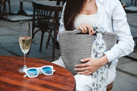 Beautiful young brunette woman wearing in white clothes, holding knitted bag on the background of old wooden doors. Copy, empty space for text.の写真素材
