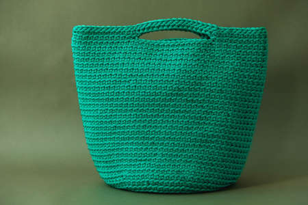 Stylish woman's knitted green bag on green background. Copy, empty space for text.の写真素材