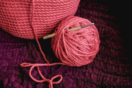 Ball of pink thread with a needle and knitted fabric on a background of purple material. Copy, empty space for text.の写真素材