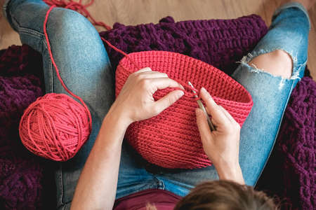 Hands woman in a cozy home setting knits from a pink thread. Top view. Copy, empty space for text.の写真素材