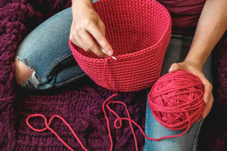 Hands woman in a cozy home setting knits from a pink thread. Top view. Copy, empty space for text.の写真素材