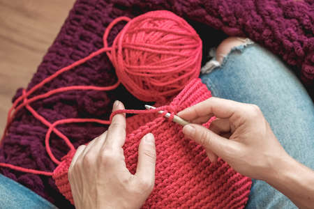 Hands woman in a cozy home setting knits from a pink thread. Top view. Copy, empty space for text.の写真素材