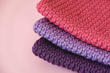 Stack of knitted material from threads of pink, red, purple colors on a pink background. Top view. Copy, empty space for text.の写真素材