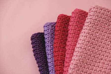 Stack of knitted material from threads of pink, red, purple colors on a pink background. Top view. Copy, empty space for text.の写真素材