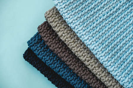 Stack of knitted material from threads of dark blue, light blue, gray colors on a blue background. Top view. Copy, empty space for text.の写真素材
