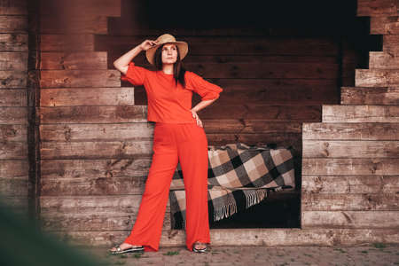 Portrait of a beautiful woman in a straw hat dressed in red clothes on a background of reeds and lake. Copy, empty space for text.の写真素材
