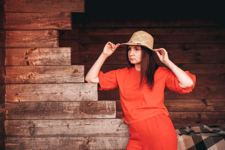 Portrait of a beautiful woman in a straw hat dressed in red clothes on a background of reeds and lake. Copy, empty space for text.の写真素材