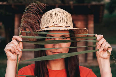 Portrait of a beautiful woman in a straw hat dressed in red clothes on a background of reeds and lake. Copy, empty space for text.の写真素材