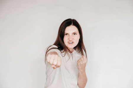 Shocked panic brunette woman dressed in casual white t shirt pulls her hands by her hair and screaming in despair and frustration, her eyes full of terror, mouth open. Copy, empty space for text.の写真素材