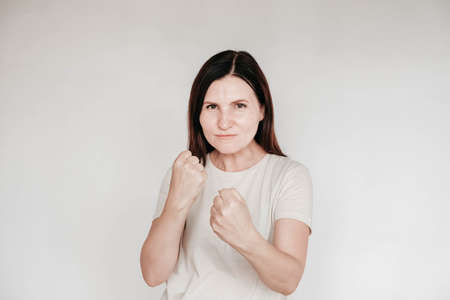 Shocked panic brunette woman dressed in casual white t shirt pulls her hands by her hair and screaming in despair and frustration, her eyes full of terror, mouth open. Copy, empty space for text.の写真素材