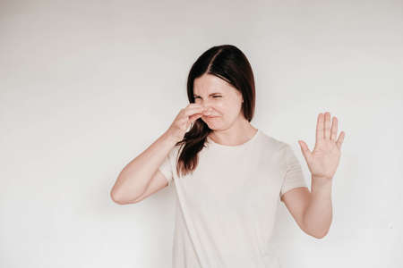 Shocked panic brunette woman dressed in casual white t shirt pulls her hands by her hair and screaming in despair and frustration, her eyes full of terror, mouth open. Copy, empty space for text.の写真素材