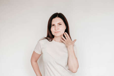 Shocked panic brunette woman dressed in casual white t shirt pulls her hands by her hair and screaming in despair and frustration, her eyes full of terror, mouth open. Copy, empty space for text.の写真素材