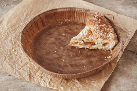 Piece of homemade apple pie in a paper plate on a wooden background. Top view. Copy, empty space for text.の写真素材