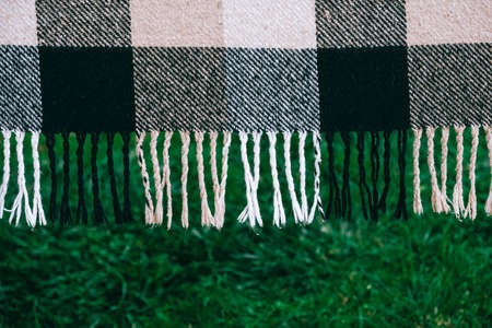 Warm plaid on a background of green grass. Copy, empty space for text.の写真素材