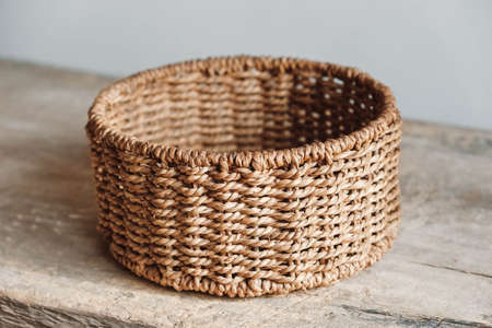 Empty round wicker basket on a old wooden table. Copy, empty space for text.の写真素材