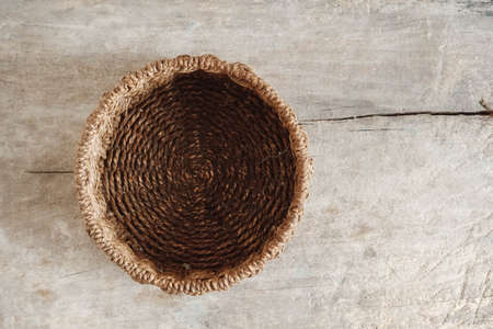 Empty round wicker basket on a old wooden background. Top view. Copy, empty space for text.の写真素材