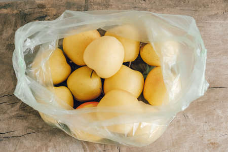 Yellow apples in a plastic bag on a wooden table. Top view. Copy, empty space for text.の写真素材