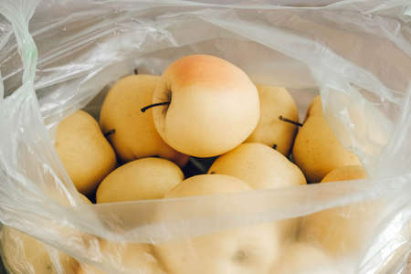 Yellow apples in a plastic bag on a wooden table. Top view. Copy, empty space for text.の写真素材