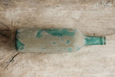 Empty glass bottle in dirt on a wooden background. Top view. Copy, empty space for text.の写真素材