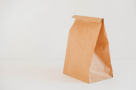 Closed disposable package made of brown kraft paper on a white background. Copy, empty space for text.の写真素材