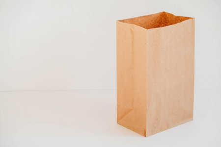 Closed disposable package made of brown kraft paper on a white background. Copy, empty space for text.の写真素材