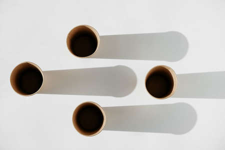 Three disposable paper cup with shadow from light on a white background. Top view. Copy, empty space for text.の写真素材