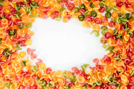 Multicolored pasta scattered on a white background in the form of a frame. Top view. Copy, empty space for text.の写真素材
