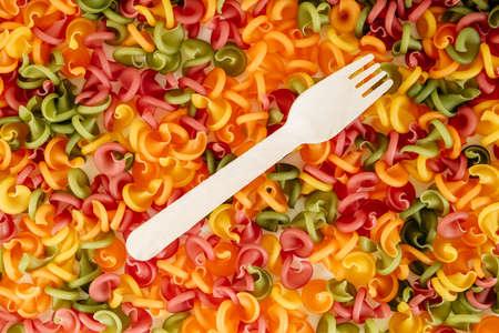 Multicolored pasta with a wooden fork as a background image. Top view. Copy, empty space for text.の写真素材