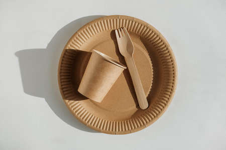 Set of disposable tableware cup, kraft paper plate and wooden fork on a white background. Eco kraft paper tableware. Recycling concept. Zero waste.の写真素材