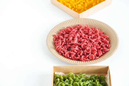 Multicolored pasta in a disposable kraft paper plates and boxes on a white background. Top view. Copy, empty space for text.の写真素材