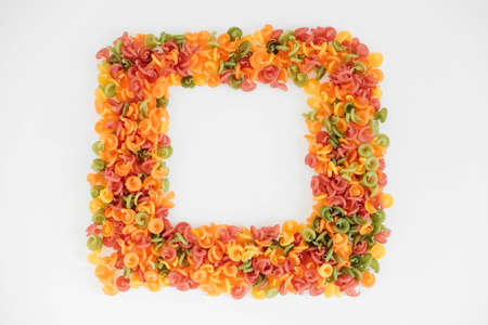 Multicolored pasta scattered on a white background in the form of a frame. Top view. Copy, empty space for text.の写真素材