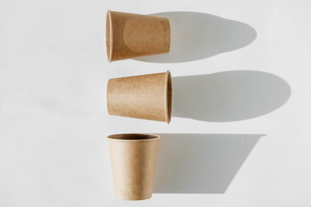 Three disposable paper cup with shadow from light on a white background. Top view. Copy, empty space for text.の写真素材