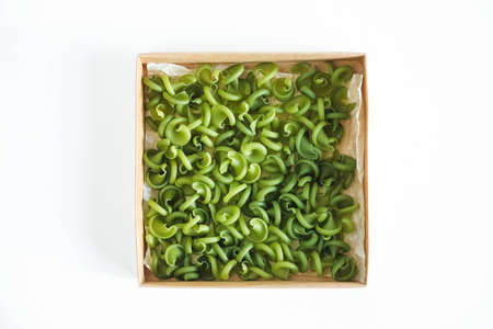 Green pasta in a cardboard box on a white background. Top view. Copy, empty space for text.の写真素材