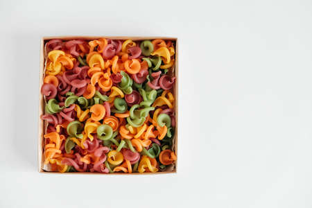 Multicolored pasta in a cardboard box on a white background. Top view. Copy, empty space for text.の写真素材