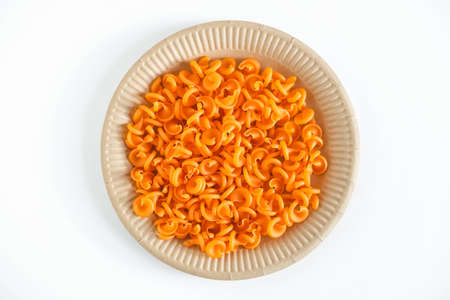Orange pasta in a disposable paper plate on a white background. Top view. Copy, empty space for text.の写真素材
