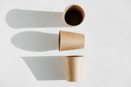 Three disposable paper cup with shadow from light on a white background. Top view. Copy, empty space...