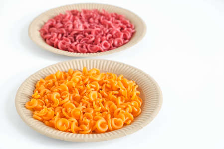 Orange and red pasta in a disposable paper plate on a white background. Top view. Copy, empty space for text.の写真素材