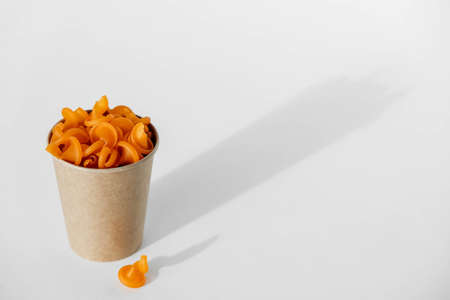 Orange pasta in a disposable kraft paper cup on a white background. Copy, empty space for text.の写真素材
