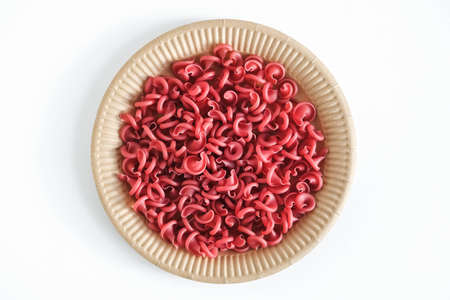 Red pasta in a disposable paper plate on a white background. Top view. Copy, empty space for text.の写真素材