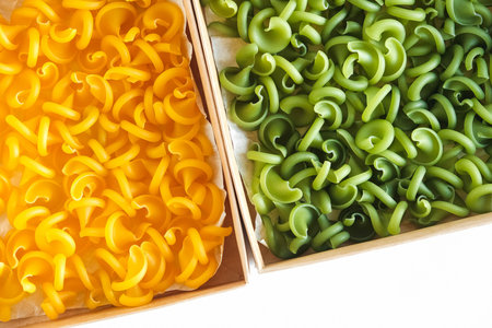Pasta yellow and green in a cardboard box on a white background. Top view. Copy, empty space for text.の写真素材