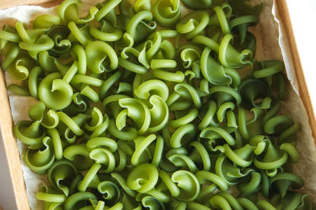 Green pasta in a cardboard box on a white background. Top view. Copy, empty space for text.の写真素材