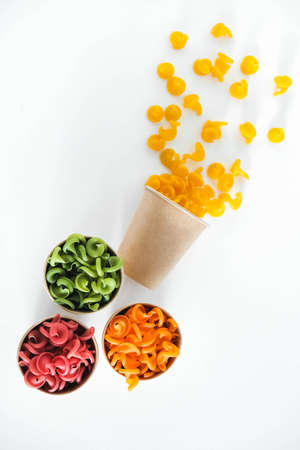 Multicolored pasta in a disposable kraft paper cups scattered on a white background. Top view. Copy, empty space for text.の写真素材