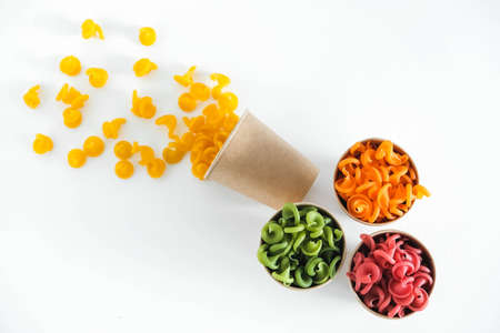 Multicolored pasta in a disposable kraft paper cups scattered on a white background. Top view. Copy, empty space for text.の写真素材