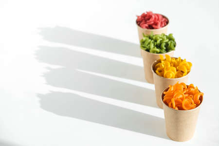 Multicolored pasta in a disposable kraft paper cups scattered on a white background. Top view. Copy, empty space for text.の写真素材