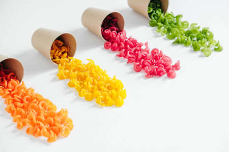 Multicolored pasta in a disposable kraft paper cups scattered on a white background. Top view. Copy, empty space for text.の写真素材